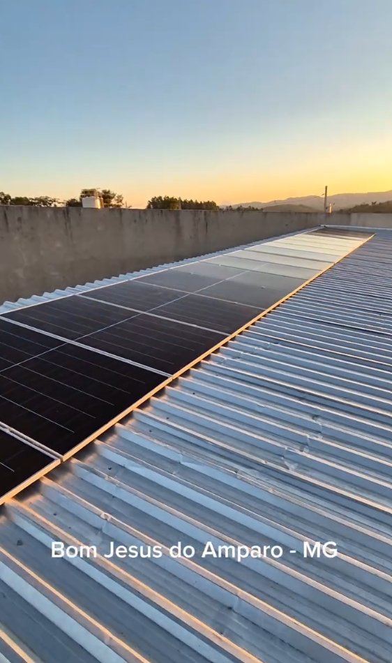 Módulos fotovoltaicos sobre telhado metálico ao pôr do sol em Bom Jesus do Amparo, Minas Gerais